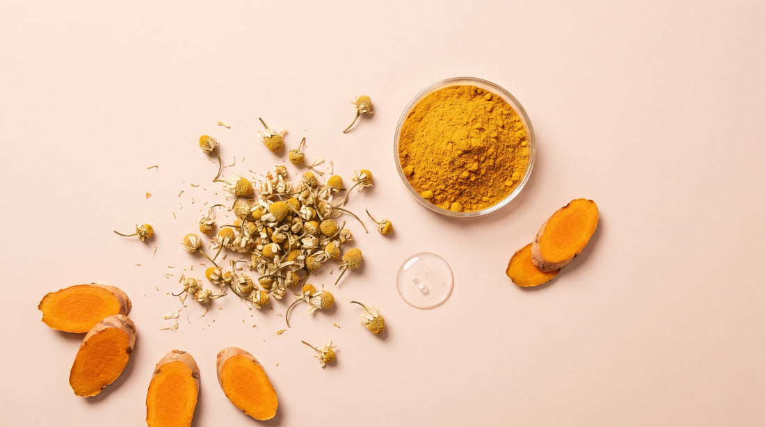 Chamomile flowers and ground turmeric arranged on a soft pink surface