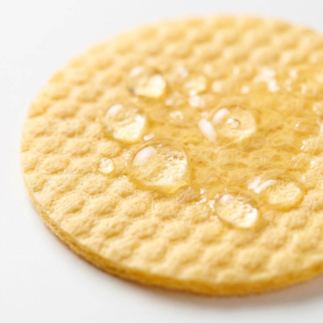Close-up of the textured side of a Veliena pad with droplets of the formula