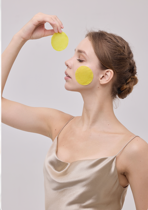 A Veliena brightening pad held up beside the face