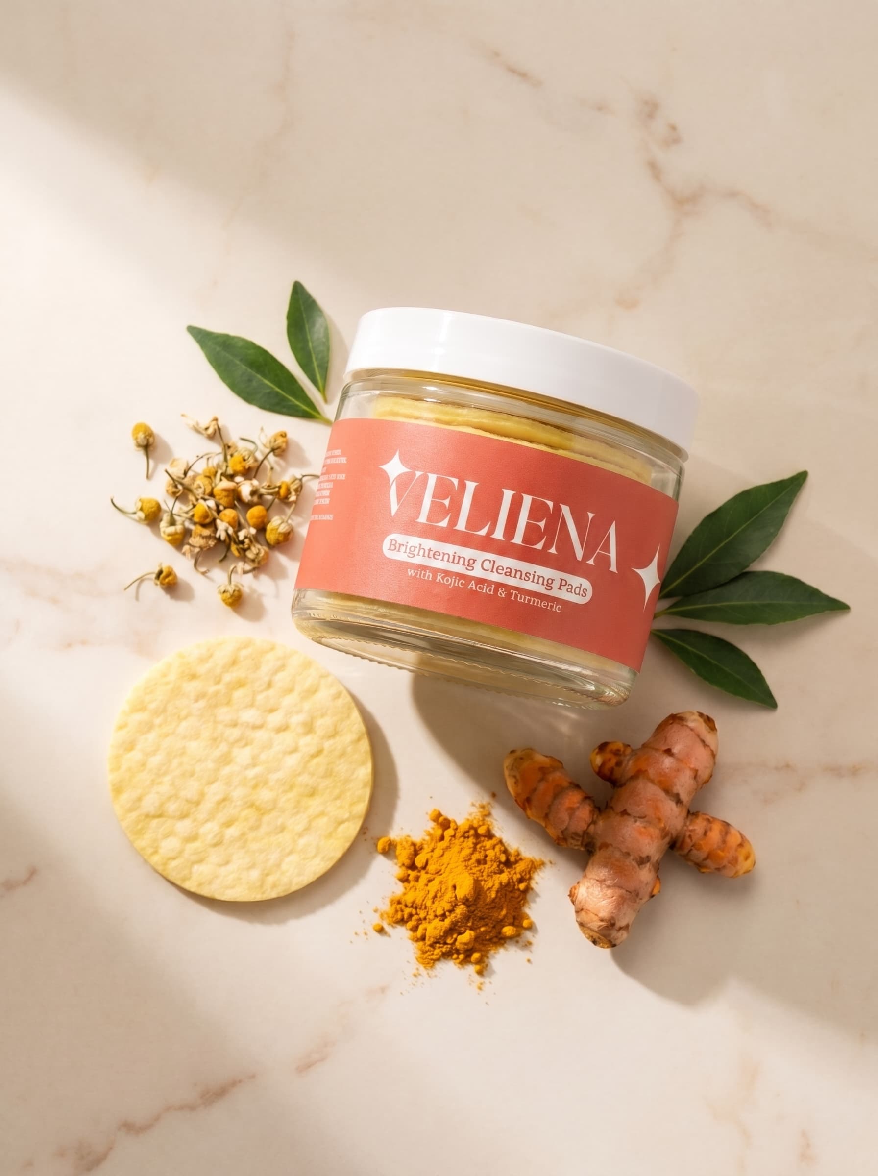 Veliena Brightening Cleansing Pads jar with a pad, turmeric root and chamomile flowers on marble