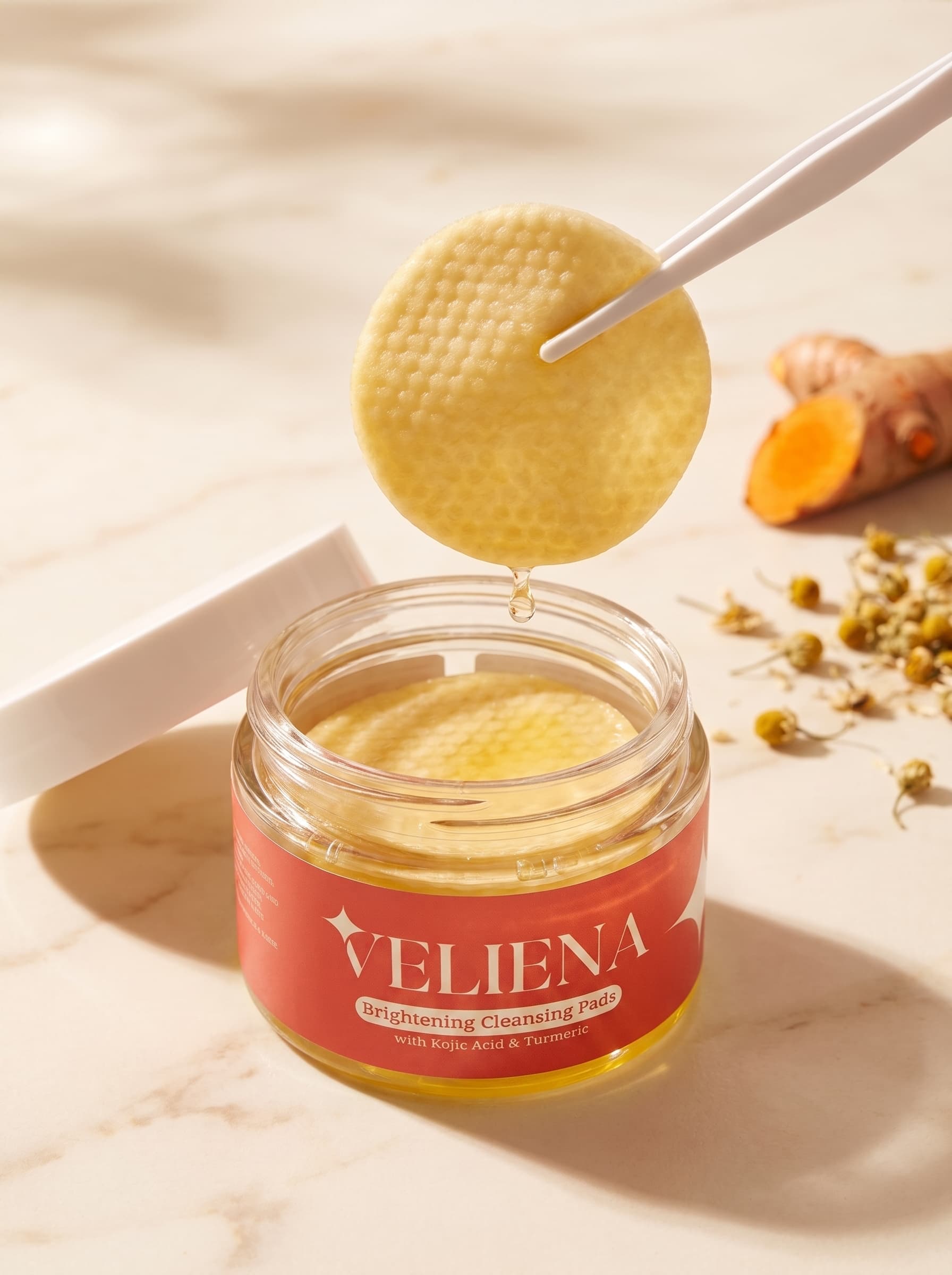 The included tweezers lifting a pre-soaked Veliena brightening pad out of the jar